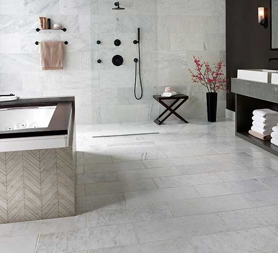 Modern open bathroom with chevron pattern tub surround, marble floor and shower enclosure